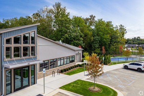the exterior of a building with a parking lot and a tennis court
